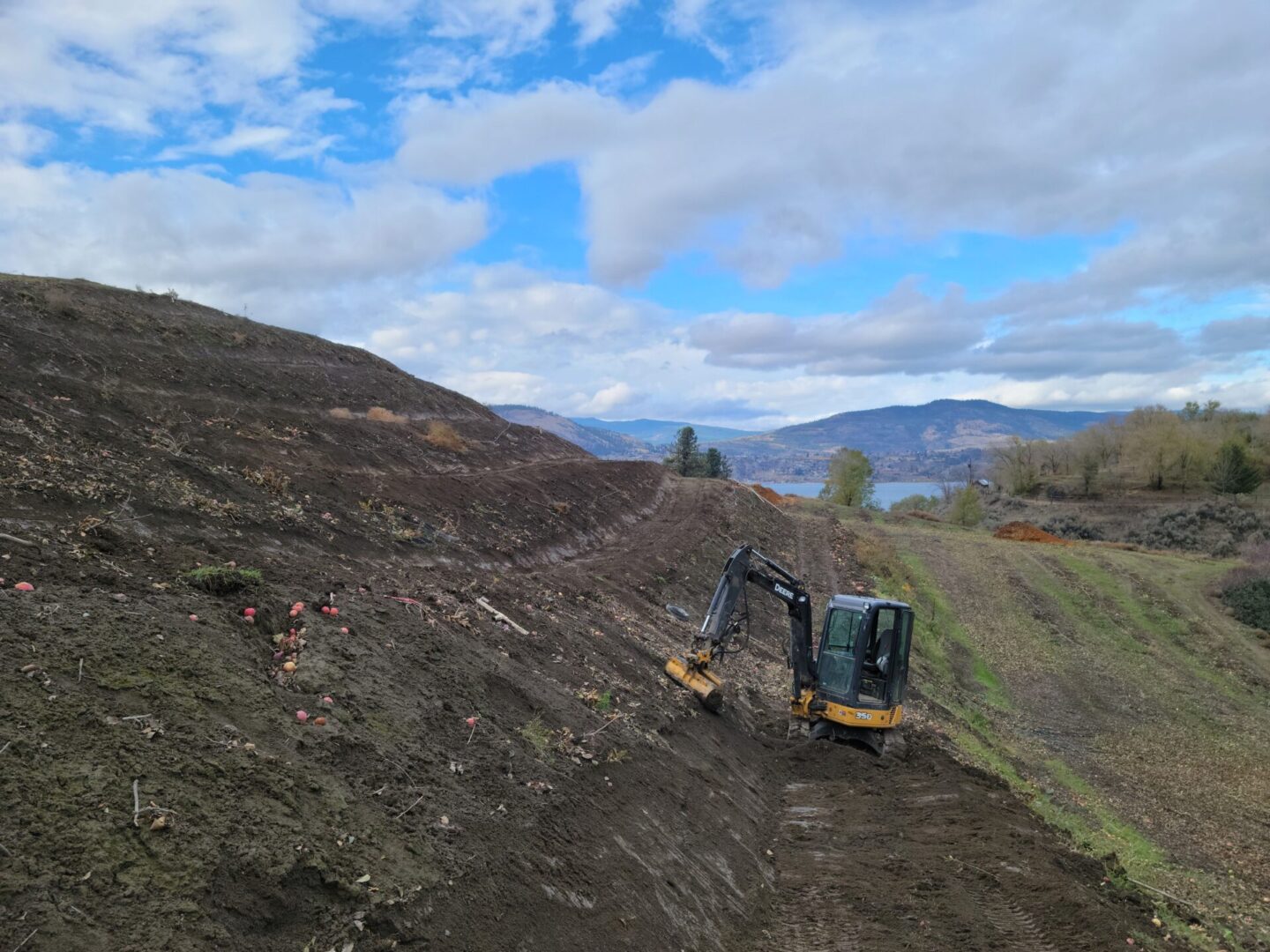 A yellow and black tractor is on the side of a hill