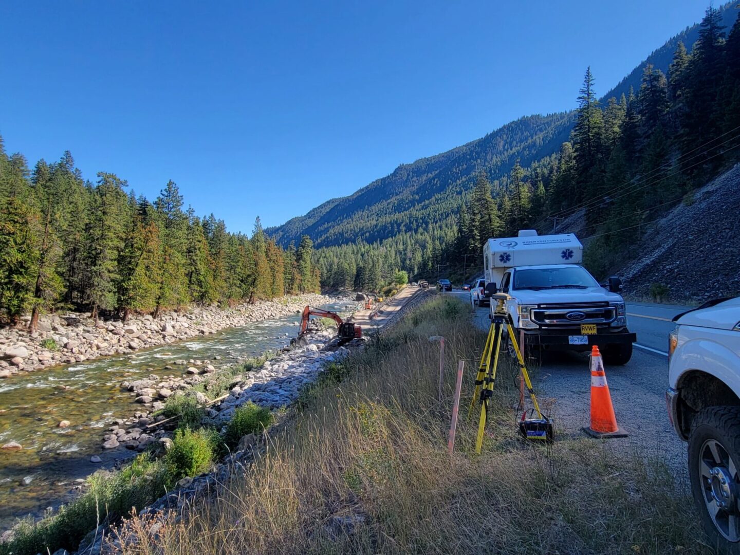 A truck and some trees near the side of a river.