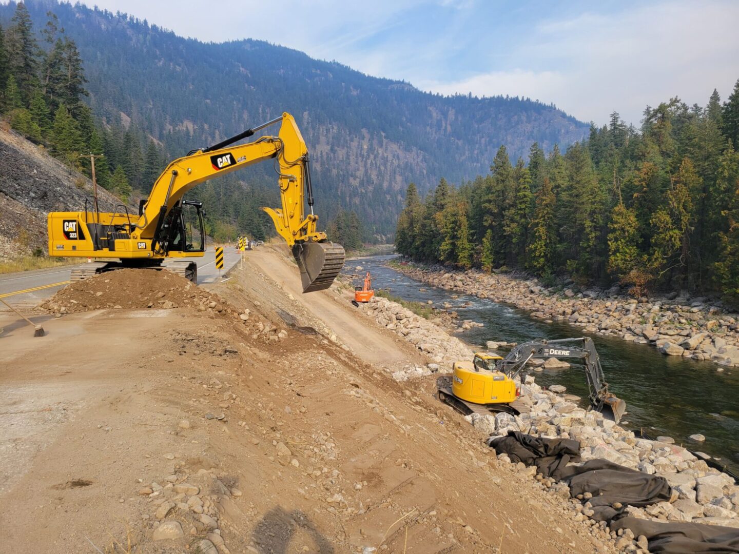 A yellow and black excavator on top of a dirt hill.