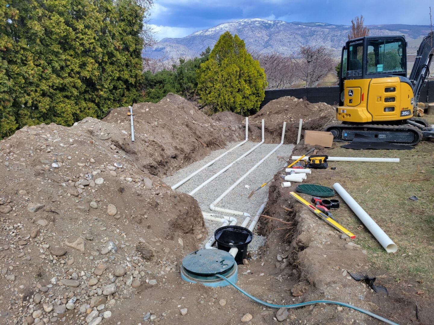 A construction site with a yellow tractor and a pipe laying on the ground.
