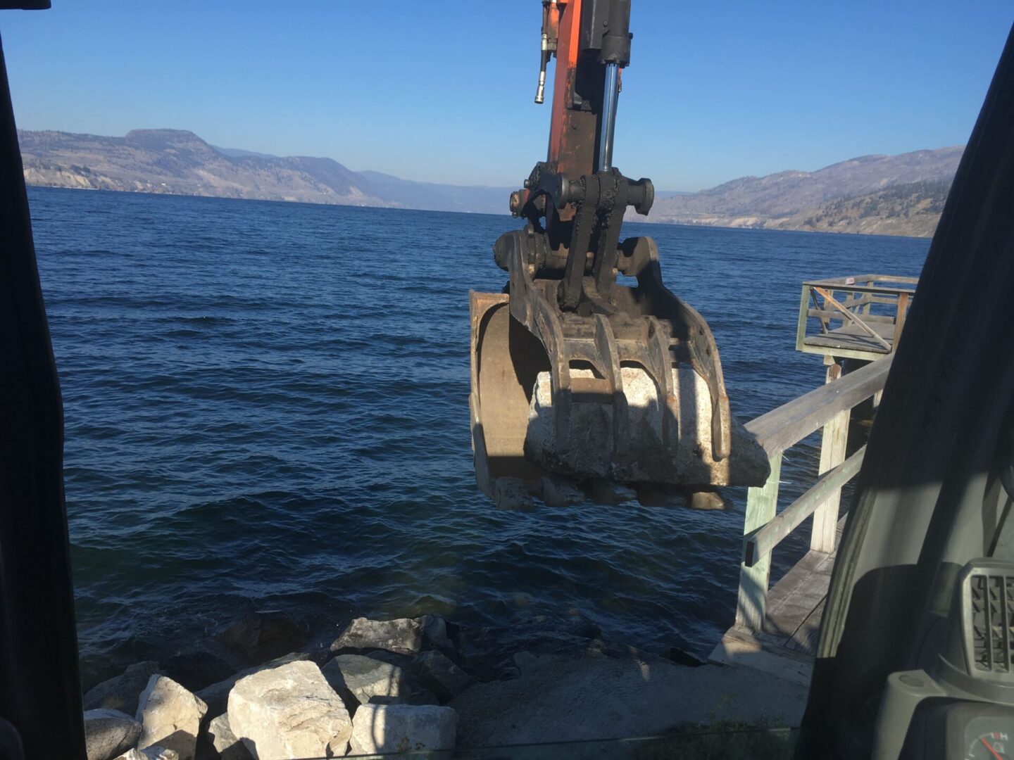 A crane is lifting rocks out of the water.